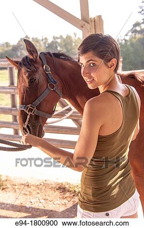Young woman brushing a horse in a barn View Large Photo Image Stock Image - Young woman brushing a horse in a barn. Fotosearch
