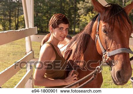 Young woman brushing a horse in a barn View Large Photo Image Stock Image - Young woman brushing a horse in a barn. Fotosearch
