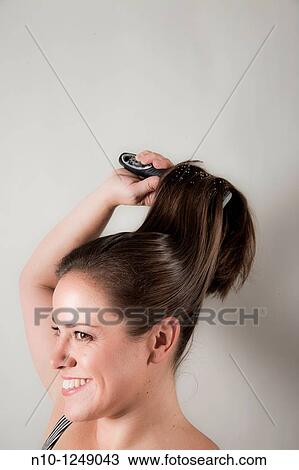 Young woman brushing her hair View Large Photo Image Stock Image - Young woman brushing her hair. Fotosearch