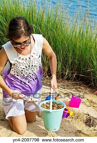 Young woman building a sandcastle. View Large Photo Image Stock Photo - Young woman building a sandcastle.. Fotosearch