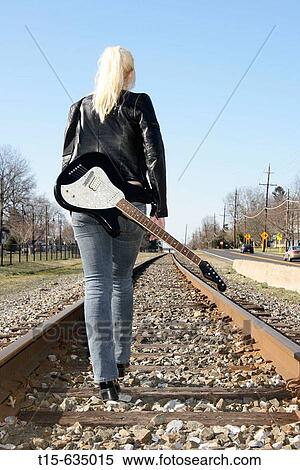 Young woman carrying a guitar standing on railroads looking into and thinking about future View Large Photo Image Stock Photography - Young woman carrying a guitar standing on railroads looking into and thinking about future. Fotosearch