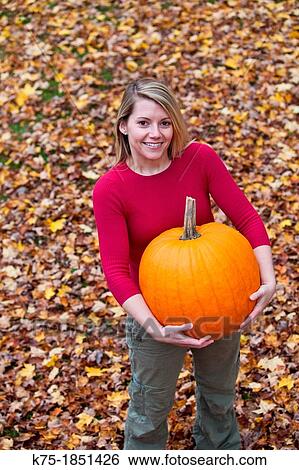Young woman carrying a large pumpkin View Large Photo Image Stock Photograph - Young woman carrying a large pumpkin. Fotosearch