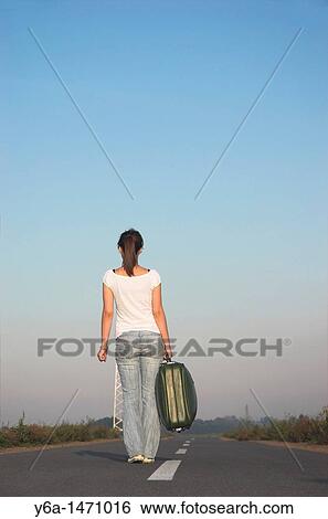 Young woman carrying suitcases on road, rear view View Large Photo Image Stock Photograph - Young woman carrying suitcases on road, rear view. Fotosearch