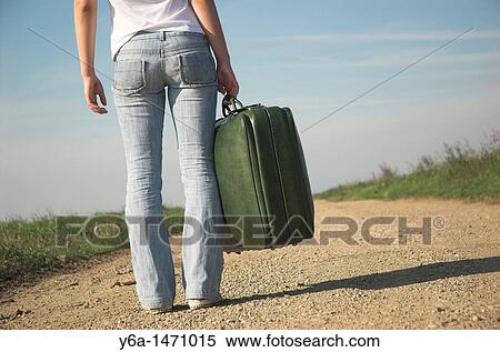 Young woman carrying suitcases on country road, rear view View Large Photo Image Stock Photography - Young woman carrying suitcases on country road, rear view. Fotosearch