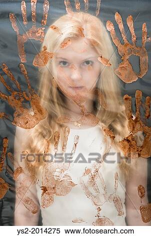 Stock Photography - Young woman caught behind plastic sheet that is covered with red handprints.. Fotosearch