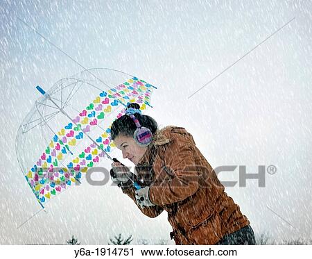 Stock Image - Young woman caught up in a snow storm. Fotosearch