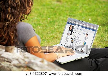 Young woman checking Facebook page online on a laptop alone at the park View Large Photo Image Stock Photo - Young woman checking Facebook page online on a laptop alone at the park. Fotosearch
