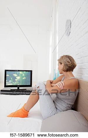 Young woman chilling out on her bed watching TV View Large Photo Image Stock Image - Young woman chilling out on her bed watching TV. Fotosearch