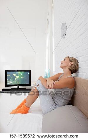 Young woman chilling out on her bed watching TV View Large Photo Image Stock Image - Young woman chilling out on her bed watching TV. Fotosearch