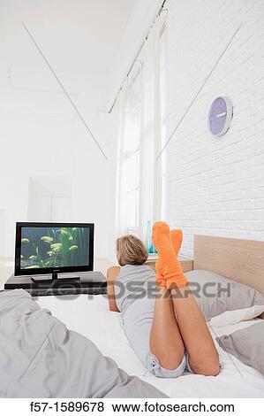 Young woman chilling out on her bed watching TV View Large Photo Image Stock Photo - Young woman chilling out on her bed watching TV. Fotosearch