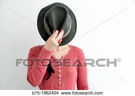 Young woman covering her face with a hat View Large Photo Image Picture - Young woman covering her face with a hat. Fotosearch