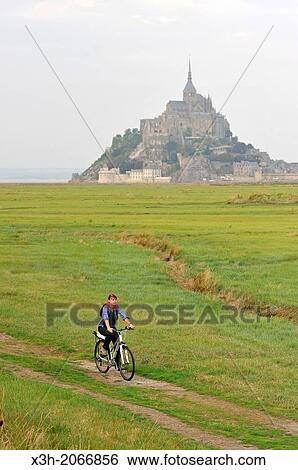 Stock Photograph - young woman cycling in the bay of Mont Saint-Michel, Manche department, Low Normandy region, France, Europe.. Fotosearch