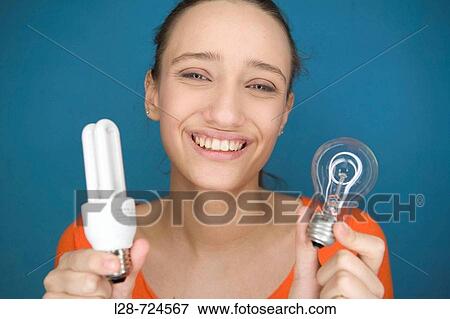 Young woman deciding between compact fluorescent bulb and regular light bulb View Large Photo Image Stock Photo - Young woman deciding between compact fluorescent bulb and regular light bulb. Fotosearch