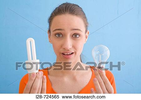 Young woman deciding between compact fluorescent bulb and regular light bulb View Large Photo Image Stock Photography - Young woman deciding between compact fluorescent bulb and regular light bulb. Fotosearch