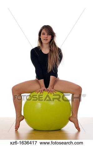 Stock Photo - young woman doing exercise, gymnastics, with a large green ball, giant ball. Fotosearch