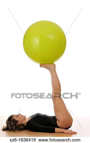 Stock Photo - young woman doing exercise, gymnastics, with a large green ball, giant ball. Fotosearch