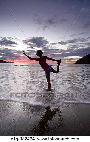 Picture - Young woman doing yoga at the beach during sunset in Playas del Coco, Costa Rica. Fotosearch