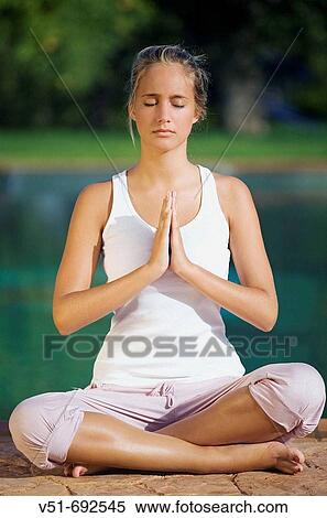 Stock Photography - Young woman doing yoga on a pool deck. Fotosearch