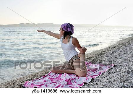 Stock Photograph - Young woman doing yoga on beach. Fotosearch