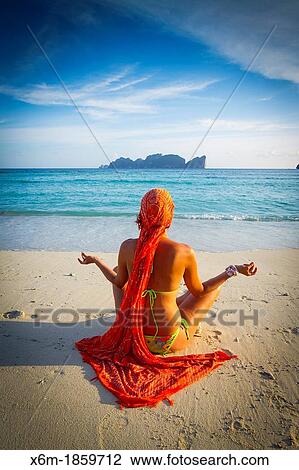 Stock Image - Young woman doing yoga on the beach Long beach Phi Phi Don island Krabi province, Andaman Sea, Thailand. Fotosearch