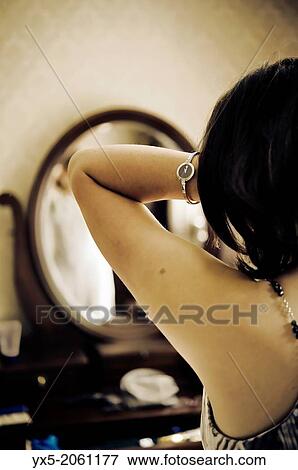 Stock Photo - Young woman dressing in front of a vanity mirror.. Fotosearch