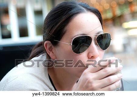 Young woman drinking coffee in an outdoors cafe View Large Photo Image Picture - Young woman drinking coffee in an outdoors cafe. Fotosearch