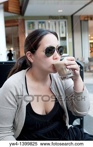 Young woman drinking coffee in an outdoors cafe View Large Photo Image Stock Photography - Young woman drinking coffee in an outdoors cafe. Fotosearch