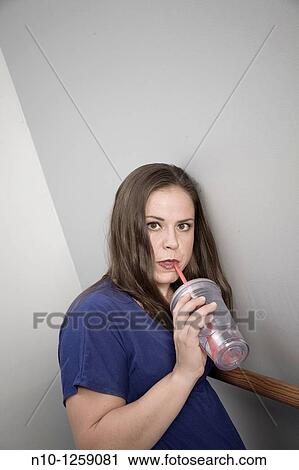 Young woman drinking from a straw in a plastic cup View Large Photo Image Stock Image - Young woman drinking from a straw in a plastic cup. Fotosearch