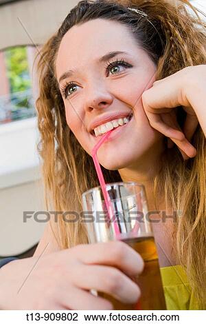 Stock Image - Young woman drinking juice through straw. Fotosearch