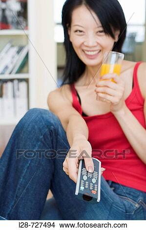 Young woman drinking orange juice and watching tv View Large Photo Image Picture - Young woman drinking orange juice and watching tv. Fotosearch