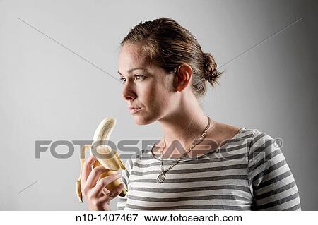 Young woman eating a banana View Large Photo Image Stock Photo - Young woman eating a banana. Fotosearch