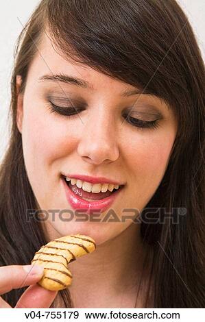 Stock Photo - Young woman eating a cookie. Fotosearch