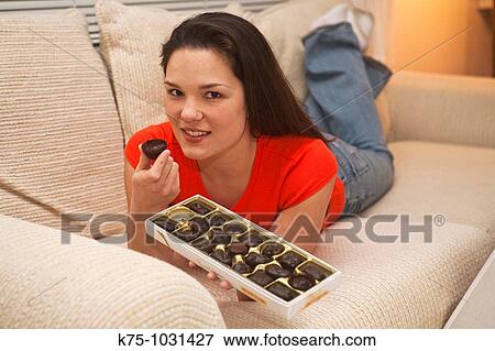 young woman eating chocolate on couch View Large Photo Image Stock Photo - young woman eating chocolate on couch. Fotosearch
