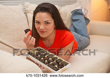 young woman eating chocolate on couch View Large Photo Image Stock Photograph - young woman eating chocolate on couch. Fotosearch