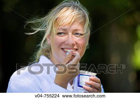 Young woman eating yoghurt smiling broadly View Large Photo Image Picture - Young woman eating yoghurt smiling broadly. Fotosearch