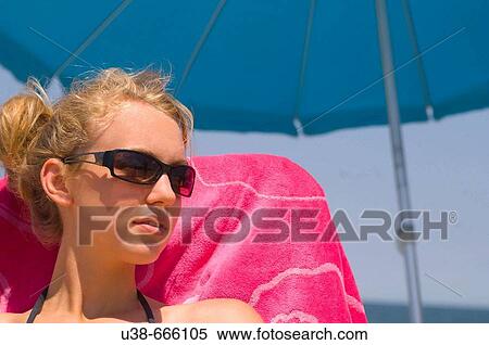 Young woman enjoying sitting at the beach under an umbrella. Sandbridge Beach, Virginia Beach, Virginia, USA View Large Photo Image Stock Photography - Young woman enjoying sitting at the beach under an umbrella. Sandbridge Beach, Virginia Beach, Virginia, USA. Fotosearch