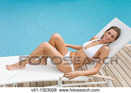 Stock Photo - Young woman enjoying sun in hammock by the pool. Fotosearch