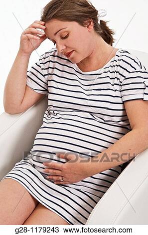 Young woman expecting a baby in blue striped dress sitting in a white armchair, looking tired and resting View Large Photo Image Stock Image - Young woman expecting a baby in blue striped dress sitting in a white armchair, looking tired and resting. Fotosearch