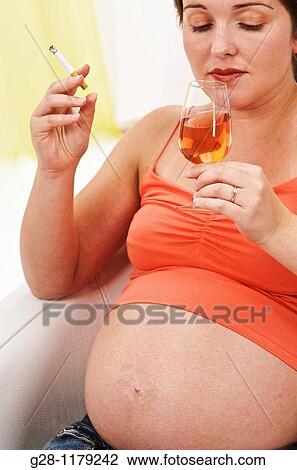 Young woman expecting a baby in orange sitting in a white armchair, smoking and drinking alcool View Large Photo Image Stock Image - Young woman expecting a baby in orange sitting in a white armchair, smoking and drinking alcool. Fotosearch