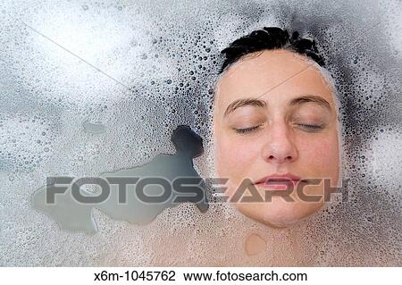 Stock Image - young woman face having a bath. Fotosearch