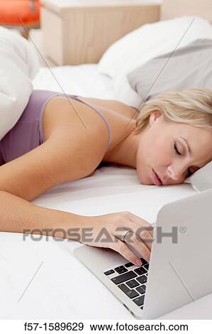 Stock Photo - Young woman fallen asleep while on her laptop. Fotosearch