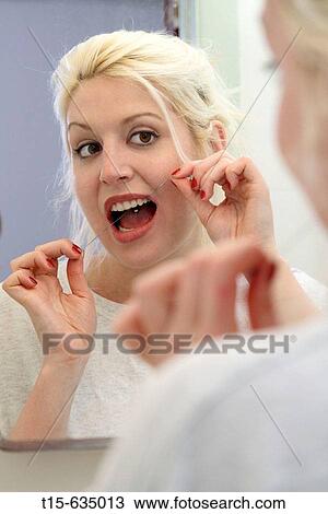 Young woman flossing in front of a mirror in bathroom View Large Photo Image Stock Image - Young woman flossing in front of a mirror in bathroom. Fotosearch