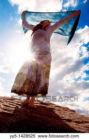 Young woman, from light, holding a handkerchief in his hand, standing on the rock View Large Photo Image Stock Photography - Young woman, from light, holding a handkerchief in his hand, standing on the rock. Fotosearch