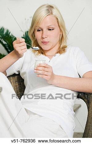 Young woman gesturing while she is having a yogurt View Large Photo Image Stock Photograph - Young woman gesturing while she is having a yogurt. Fotosearch