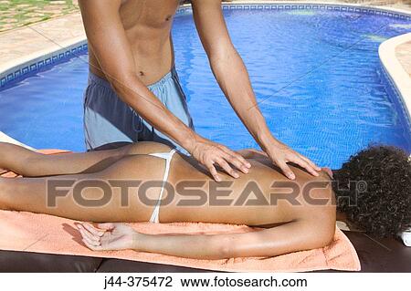 Stock Image - Young woman getting a massage outdoor in a spa. Fotosearch