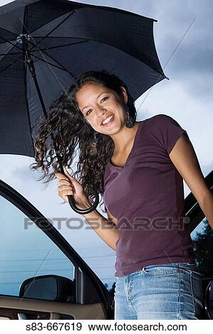 Young woman getting out of a car with an umbrella View Large Photo Image Stock Photo - Young woman getting out of a car with an umbrella. Fotosearch