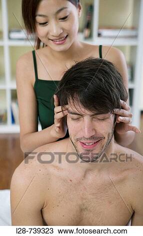 Stock Image - Young woman giving a young man a head massage. Fotosearch