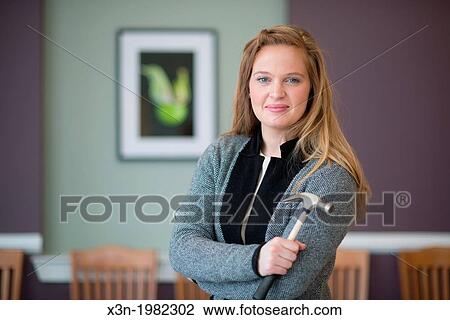 Young woman hanging photographs on wall. View Large Photo Image Stock Image - Young woman hanging photographs on wall.. Fotosearch