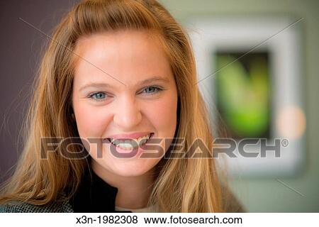 Young woman hanging photographs on wall. View Large Photo Image Stock Photo - Young woman hanging photographs on wall.. Fotosearch