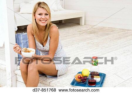 Young woman having breackfast sitting on wooden floor View Large Photo Image Stock Photo - Young woman having breackfast sitting on wooden floor. Fotosearch